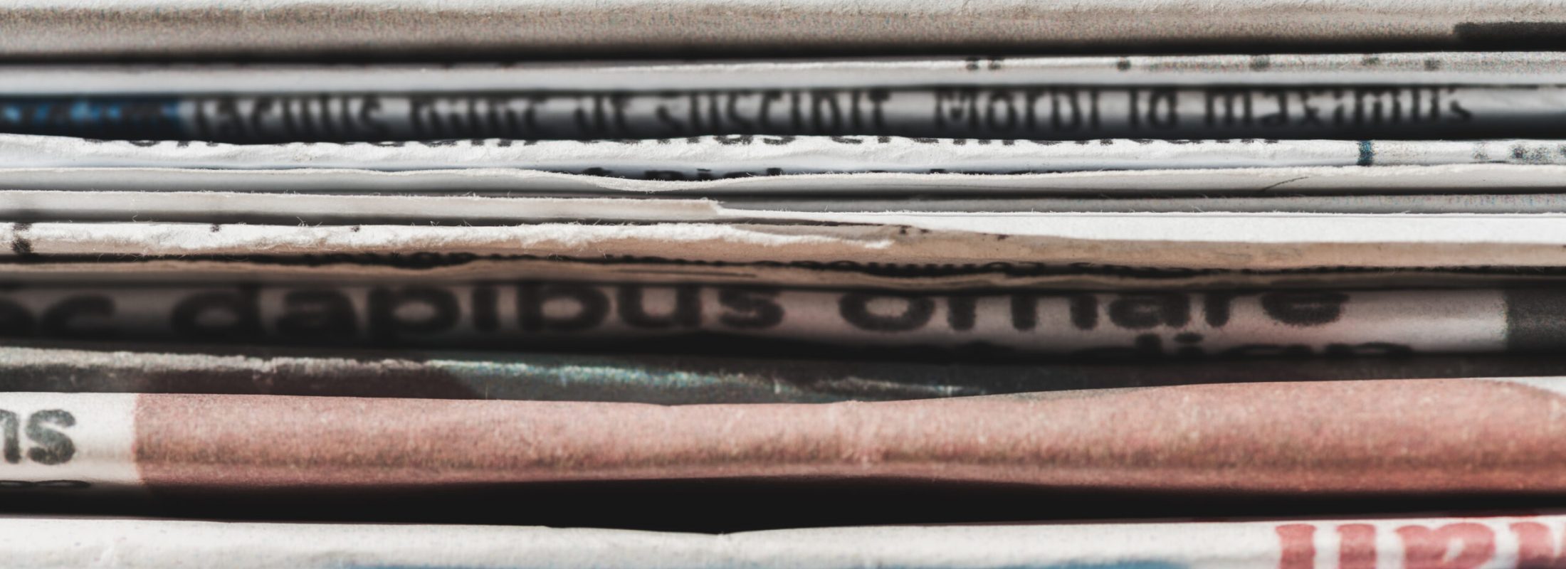 close up of different print daily newspapers in pile